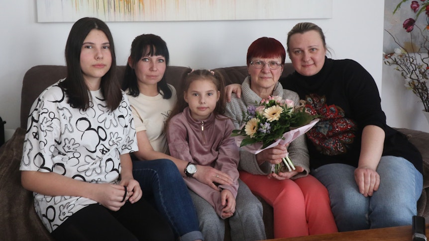 Eine ukrainische Familie sitzt auf einem Sessel und schaut in die Kamera.