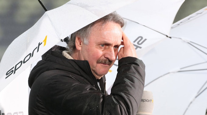 TV-Experte Peter Neururer mit Regenschirm im Stadion.