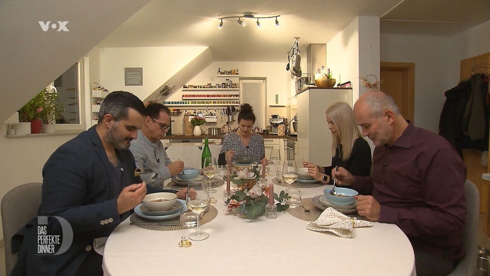 Das perfekte Dinner (Vox-Ausstrahlung 15.03.2022). Gastgeberin Amira sitzt am Kopfende des Tisches