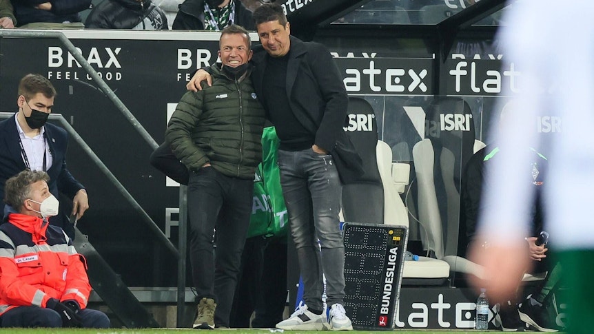 Fußballexperte Lothar Matthäus (l.) und Co-Trainer Christian Peintinger (r.) von Borussia Mönchengladbach umarmen sich beim Spiel gegen Hertha BSC am Samstag (12. März 2022) an der Seitenlinie.