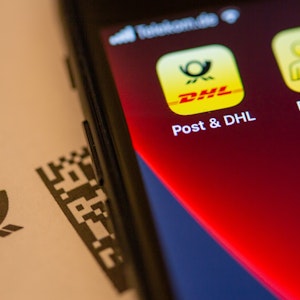 Das Logo der Post & DHL App ist auf dem Display eines Smartphones zu sehen.