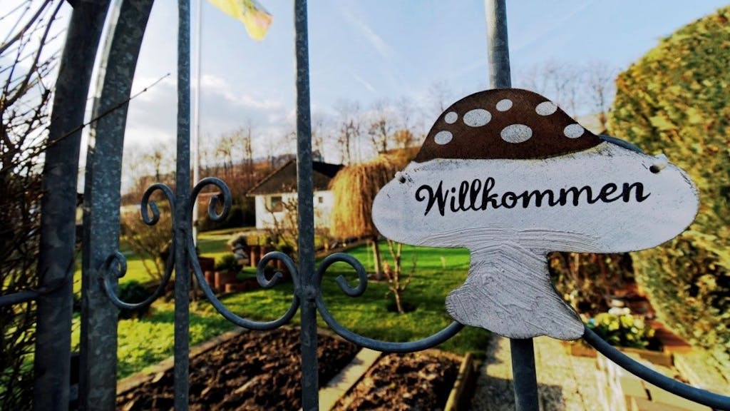 Ein Schild mit dem Schriftzug „Willkommen“ hängt am Tor eines Schrebergartens in einer Kleingartenanlage in Köln.