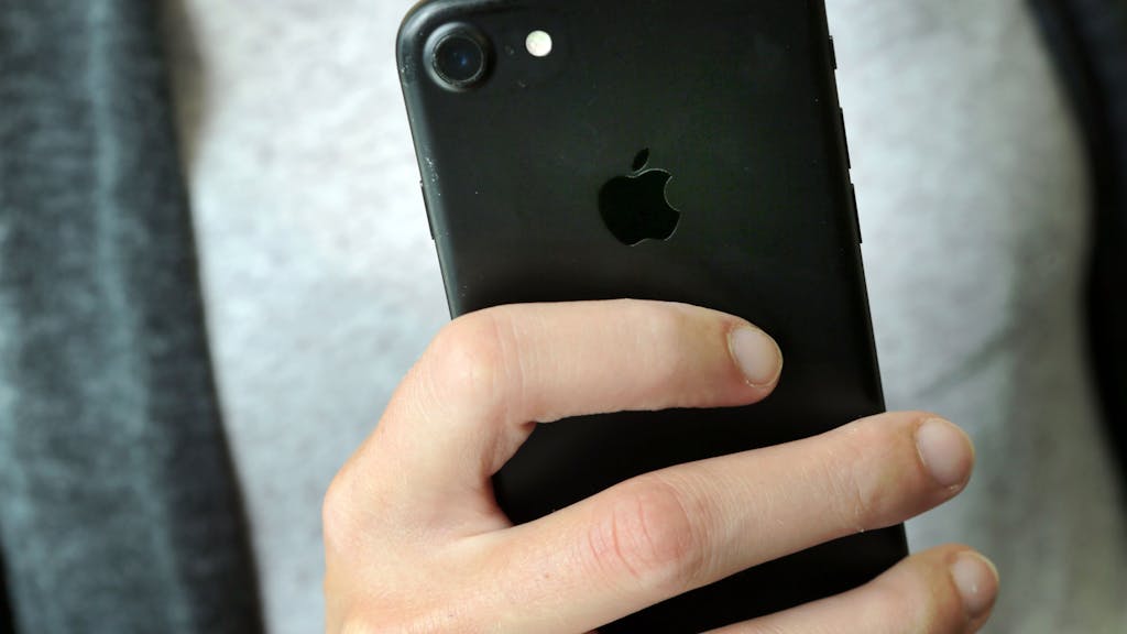 Eine Frau hält ein iPhone 7 in der Hand.