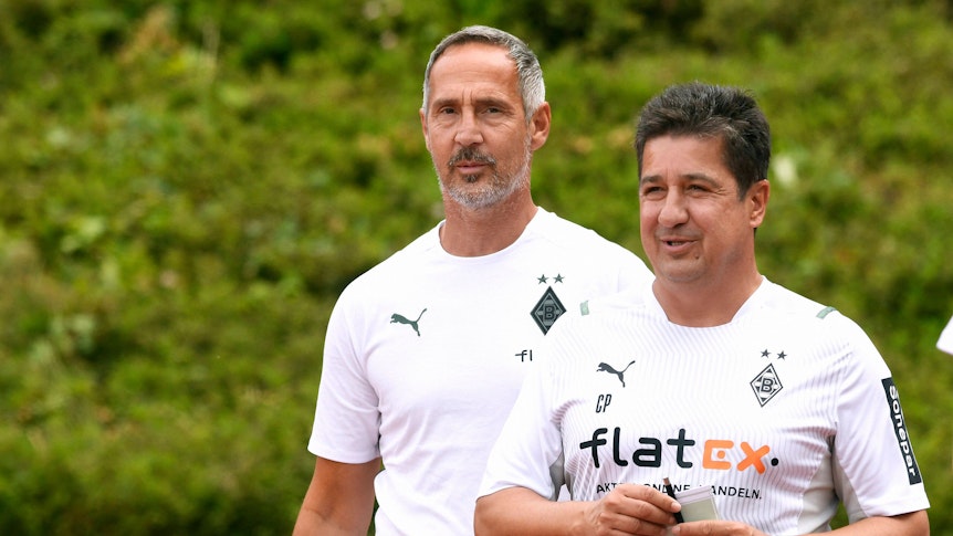 Adi Hütter (l.), Cheftrainer von Borussia Mönchengladbach, mit seinem Assistenten Christian Peintinger (r.) im Rheydter Grenzlandstadion am 10. Juli 2021. Beide lächeln.