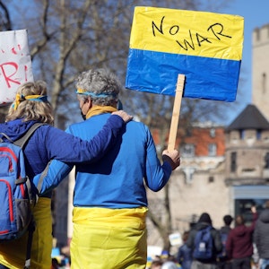 Mann und Frau zeigen Ukraine-Flagge auf einer Friedensdemo in Köln.