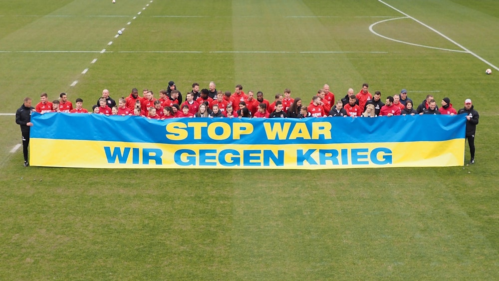 Spieler des 1. FC Köln und FK Krywbas posieren mit einem Anti-Kriegs-Banner.