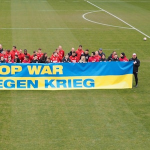 Spieler des 1. FC Köln und FK Krywbas posieren mit einem Anti-Kriegs-Banner.