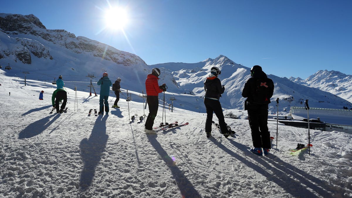 Wintersportler stehen im Skigebiet Ischgl im Sonnenschein. 