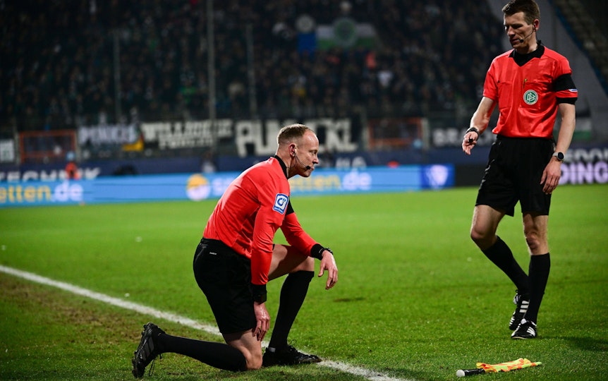 Schiedsrichter-Assistent Christian Gittelmann geht zu Boden, getroffen von einem Bierbecher im Bundesliga-Duell zwischen dem VfL Bochum und Borussia Mönchengladbach am 18, März 2022. Schiedsrichter Cortus kommt zu Hilfe.