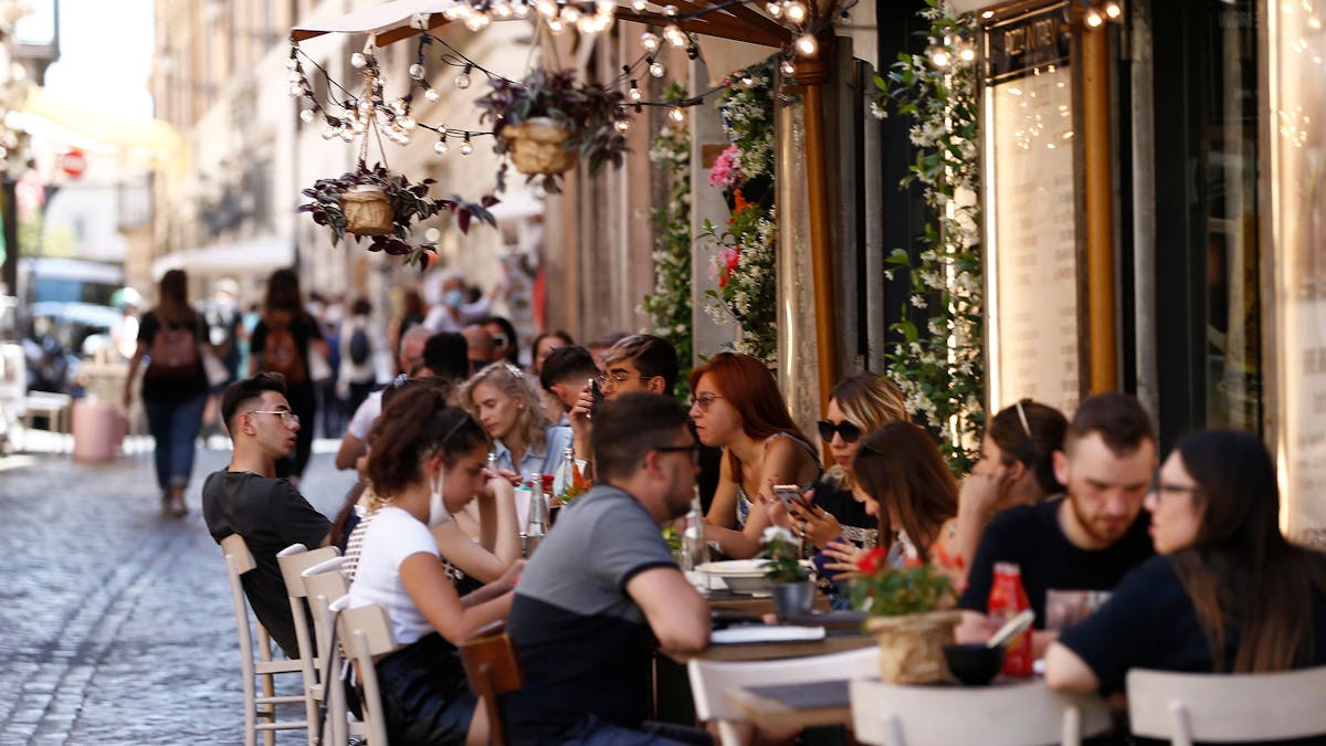 Touristen sitzen im Außenbereich eines Restaurants in der Via delle Muratte. In Rom hält der Tourismus nach und nach wieder Einkehr.