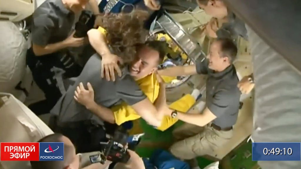 In diesem von Roskosmos zur Verfügung gestellten Video begrüßt die Besatzung der Internationalen Raumstation (ISS) drei russische Kosmonauten in gelber Kleidung, nachdem die Neuankömmlinge angedockt haben.