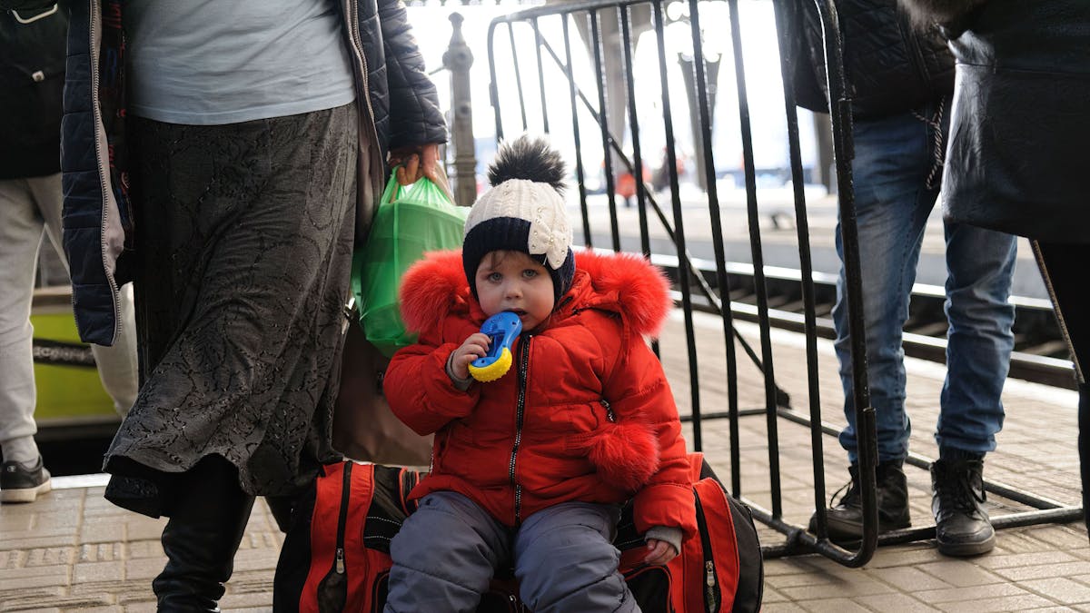 Ein Kind sitzt auf einem Gepäckstück am Bahnhof von Lwiw.