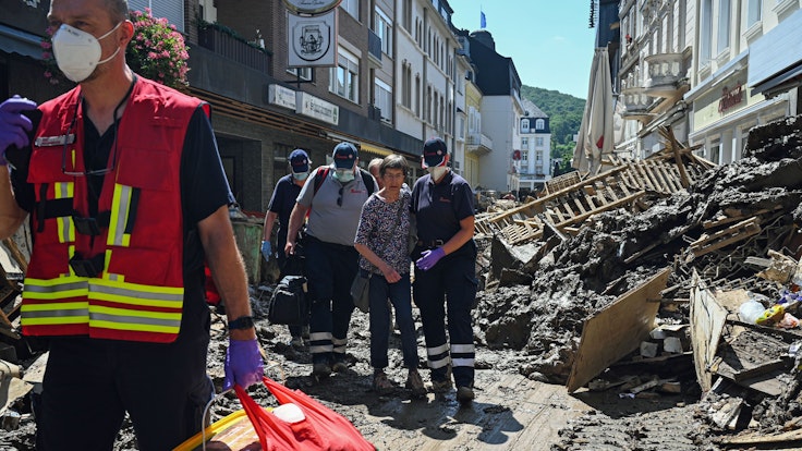 Das Foto vom 12.10.2021 zeigt Helfende der Johanniter in Bad Neuenahr-Ahrweiler, die eine Seniorin kurz nach der Flut-Katastrophe aus ihrer Wohnung begleiten.