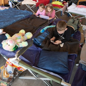 Geflüchtete Kinder aus der Ukraine liegen in der Notunterkunft auf ihren Feldbetten und vertreiben sich die Zeit.