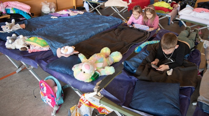 Geflüchtete Kinder aus der Ukraine liegen in der Notunterkunft auf ihren Feldbetten und vertreiben sich die Zeit.