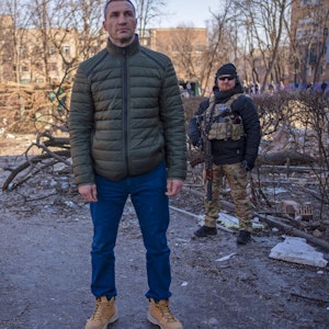 Vitali Klitschko (2.v.l), Bürgermeister von Kyjiw, tröstet eine weinende Nachbarin an dem Ort, an dem ein Bombenangriff Wohngebäude beschädigt hat, neben seinem Bruder Wladimir Klitschko (vorne).