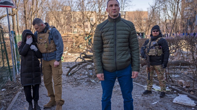 Vitali Klitschko (2.v.l), Bürgermeister von Kyjiw, tröstet eine weinende Nachbarin an dem Ort, an dem ein Bombenangriff Wohngebäude beschädigt hat, neben seinem Bruder Wladimir Klitschko (vorne).