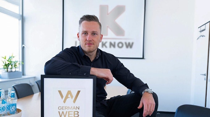 Gründer Jens Kröger sitzt in seinem Büro mit dem German Web Award.