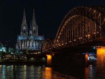 Ein Blick über den Rhein auf den erleuchteten Kölner Dom.