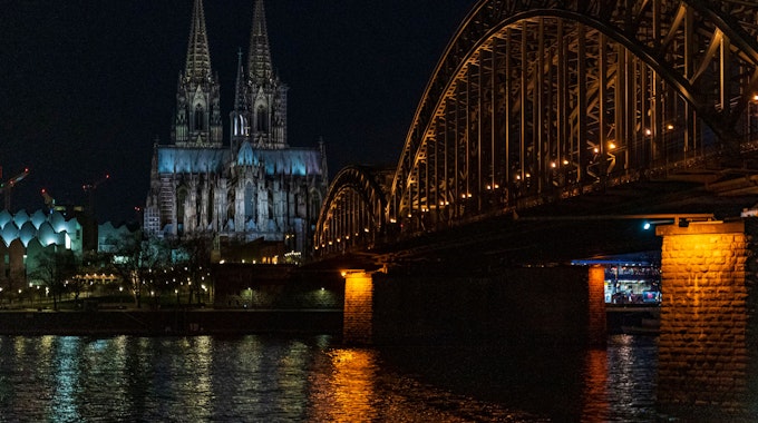 Ein Blick über den Rhein auf den erleuchteten Kölner Dom.