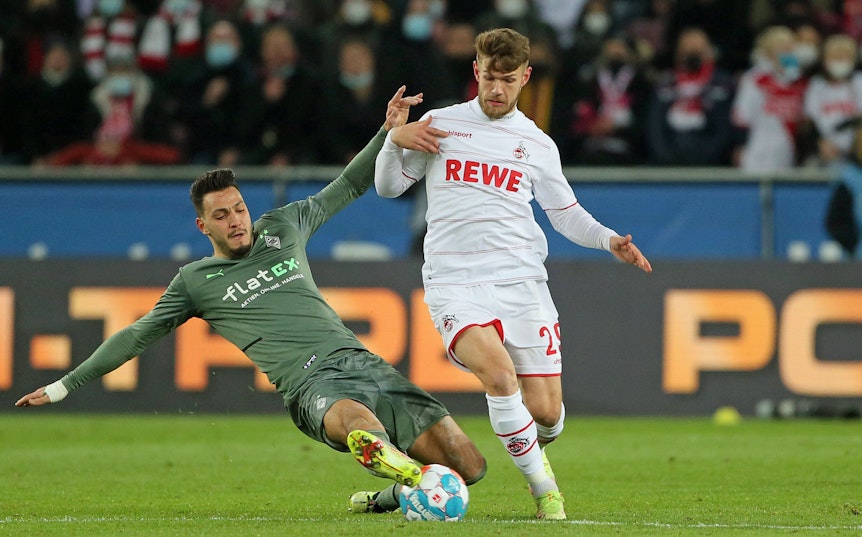 Im Hinspiel (27. November 2021) hat Borussia Mönchengladbach mit 1:4 beim 1. FC Köln verloren. In dieser Szene kämpfen Ramy Bensebaini (l.) und Jan Thielmann (r.) um den Ball. Bensebaini grätscht.