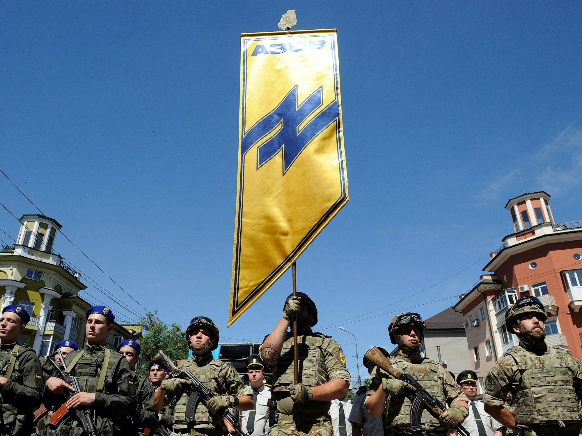Ukrainische Soldaten des Asow-Regiments halten eine Standarte mit einer Wolfsangel hoch.