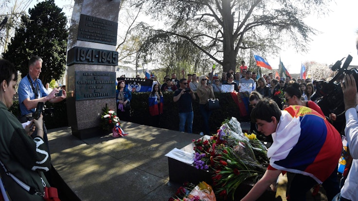 Menschen mit Russland-Fahnen legen Kränze an einem Ehrenmal nieder.