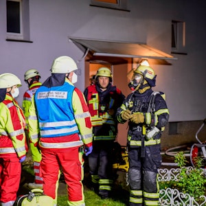 Feuerwehrleute arbeiten vor einem Haus in dem eine Wohnung gebrannt hat.