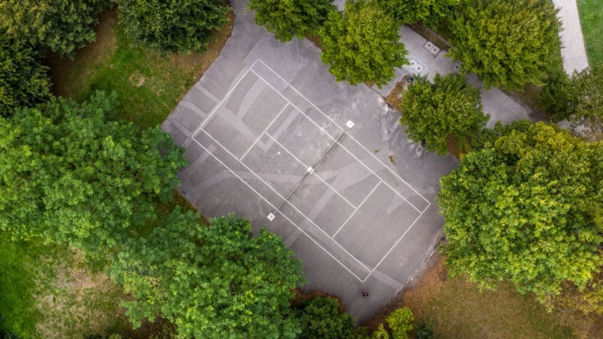 Luftaufnahme eines Tennisplatzes im Grünen.