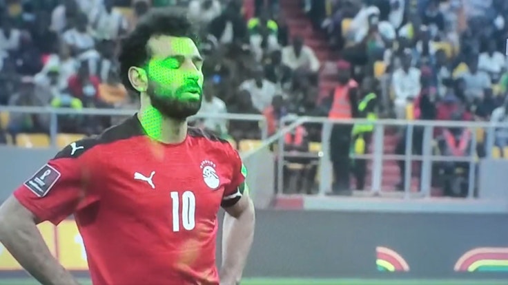 Mehrere Laserpointer sind auf das Gesicht von Mohamed Salah gerichtet.