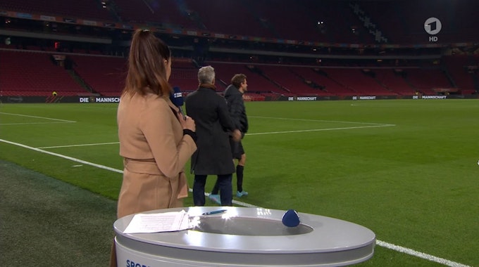Esther Sedlaczek dreht sich zu Bastian Schweinsteiger um, der nach dem DFB-Spiel in den Niederlanden mit Thomas Müller spricht.
