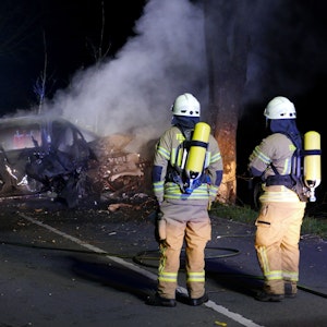 Die Feuerwehr steht vor dem Wrack eines ausgebrannten Autos, in dem zwei Menschen ums Leben gekommen sind.