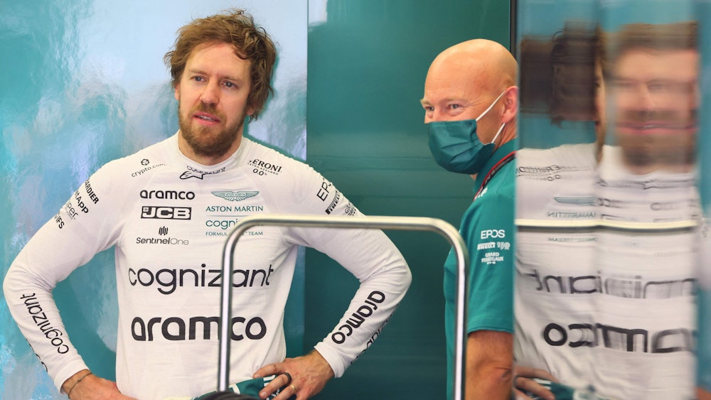 Sebastian Vettel spricht mit einem Teammitglied in der Garage des Aston Martin Teams.