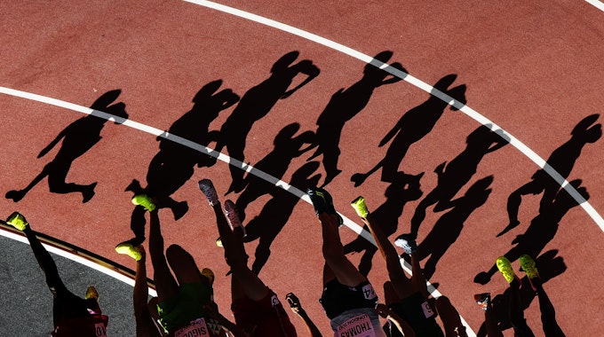 Die Schatten von Läufern sind in einer Kurve auf der Laufbahn zu sehen.