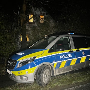 Ein Polizeiauto steht im Dunkeln vor einem Haus.