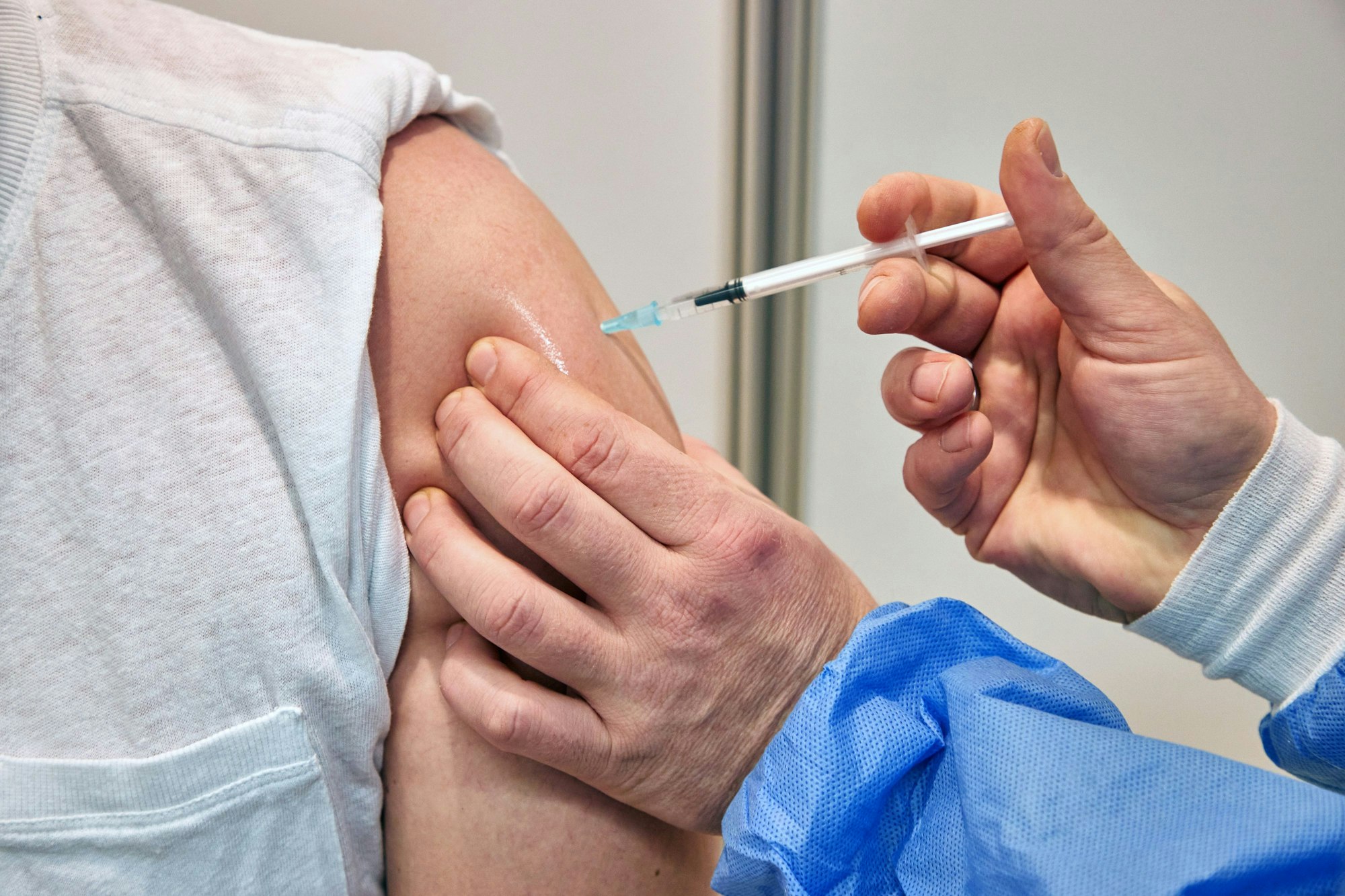 Ein Gesundheits-und Krankenpfleger verimpft in einem Impfzentrum einem Mann den Impfstoff Nuvaxovid des Pharmaunternehmens Novavax. Seit heute werden auch Corona-Impfungen mit dem neuen Impfstoff von Novavax angeboten.