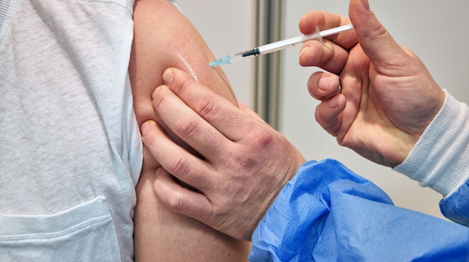 Ein Gesundheits-und Krankenpfleger verimpft in einem Impfzentrum einem Mann den Impfstoff Nuvaxovid des Pharmaunternehmens Novavax. Seit heute werden auch Corona-Impfungen mit dem neuen Impfstoff von Novavax angeboten.