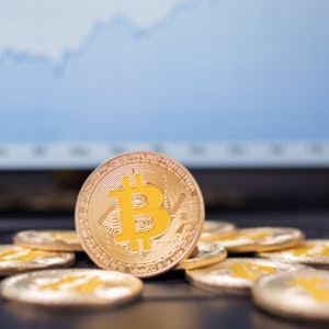 Münzen mit dem Bitcoin-Logo liegen auf der Tastatur eines Laptops.