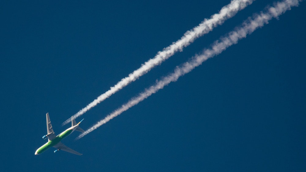 Ein Flugzeug hinterlässt am Himmel Kondensstreifen.