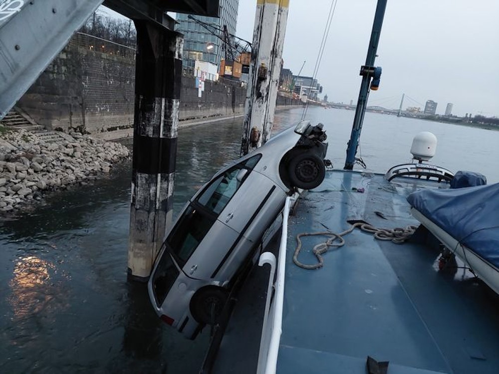 Minivan hängt an der Seite eines Schiffes am Rhein.