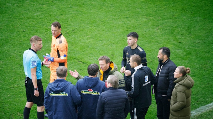 Schiedsrichter Christian Dingert (l in blau) bespricht mit dem vierten Offiziellen sowie Spielern und Verantwortlichen des FC Bayern München sowie des SC Freiburg das Vorgehen.