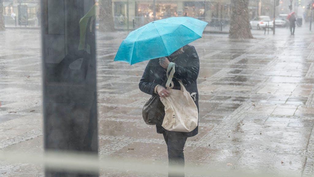 Dieses Foto ist ein Symbolbild vom 18.02.2022 in Köln und zeigt eine Person, die bei Regen einen Schirm hält.