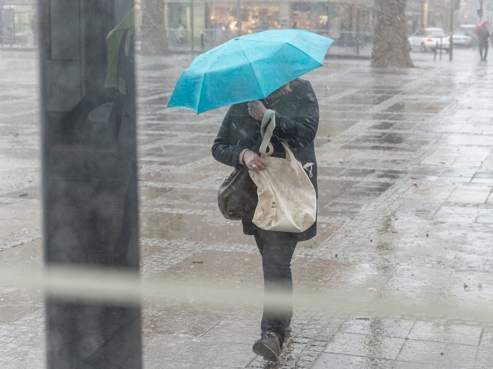 Unwetter in Köln. Eine Frau läuft mit einem Regenschirm durch die Stadt.