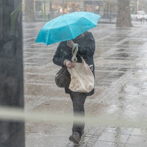 Unwetter in Köln. Eine Frau läuft mit einem Regenschirm durch die Stadt.