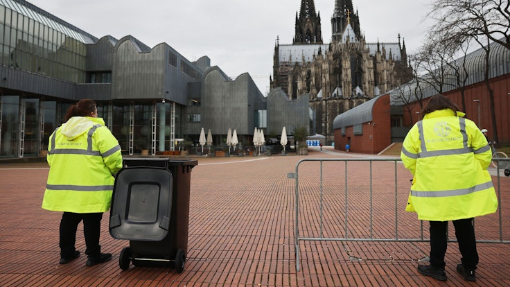 Köln ist die Heimat vieler erfolgreicher Unternehmen. Unser Foto vom 24. Februar 2022 zeigt Mitarbeiter eines Sicherheitsdienstes hinter dem Dom.