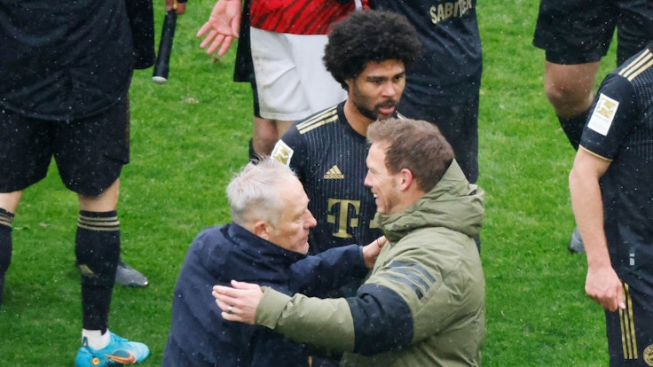 Freiburgs Trainer Christian Streich (l) und Münchens Cheftrainer Julian Nagelsmann (r) verabschieden sich nach Spielende voneinander, dahinter geht Münchens Serge Gnabry.
