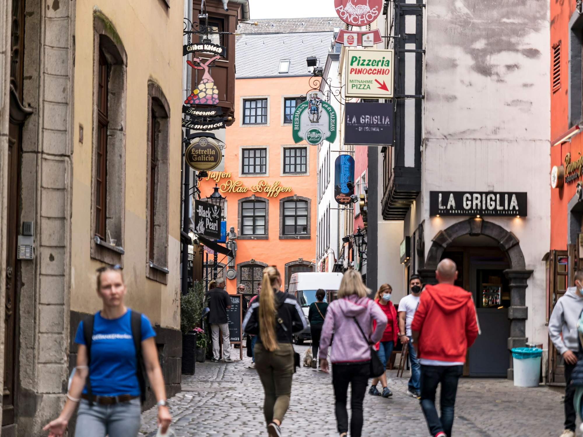 Menschen laufen über eine Straße in der Kölner Altstadt.