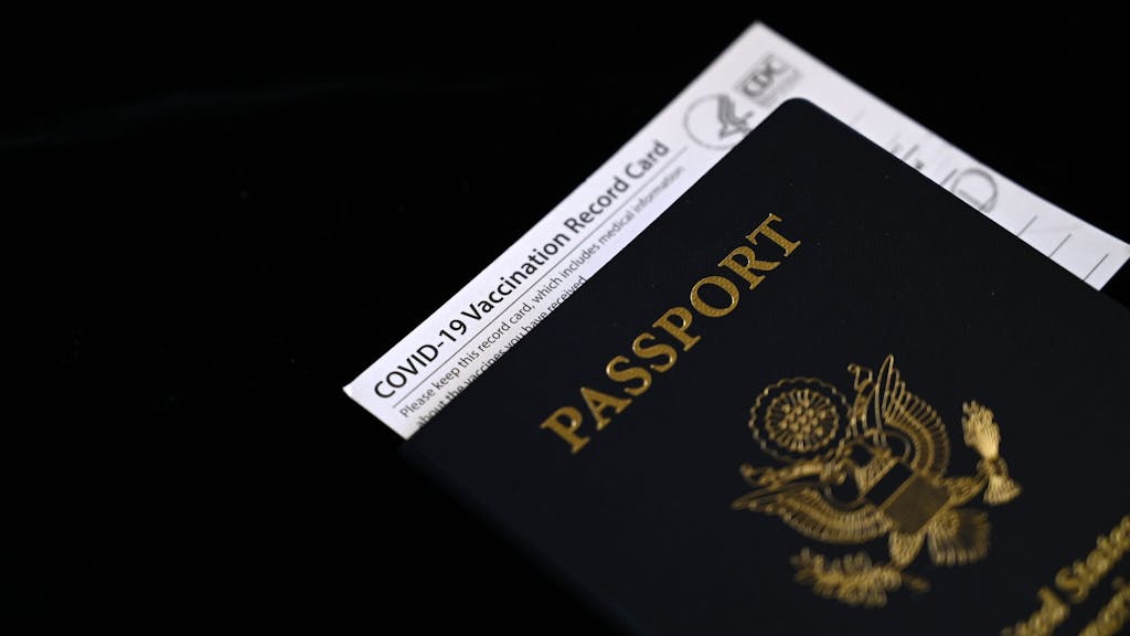 Ein Corona-Impfpass steckt in einem US-amerikanischen Reisepass.