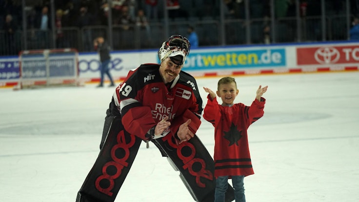 Justin Pogge (Kölner Haie) auf dem Eis mit seinem Kind.