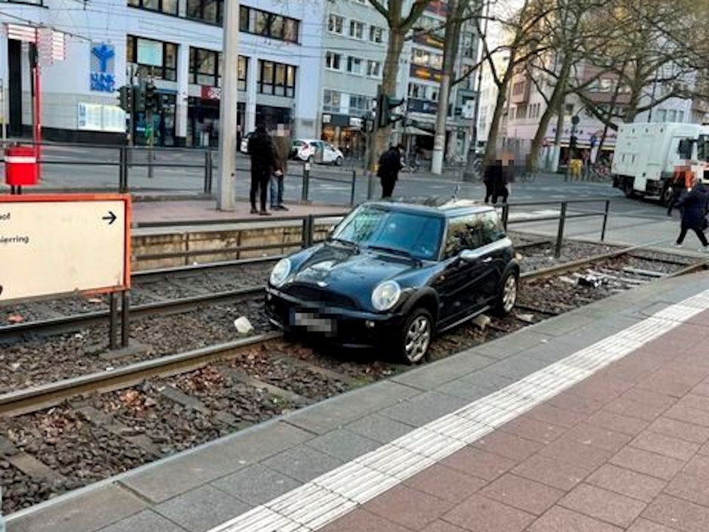 Ein Auto liegt in einem Gleisbett einer Straßenbahnhaltestelle.